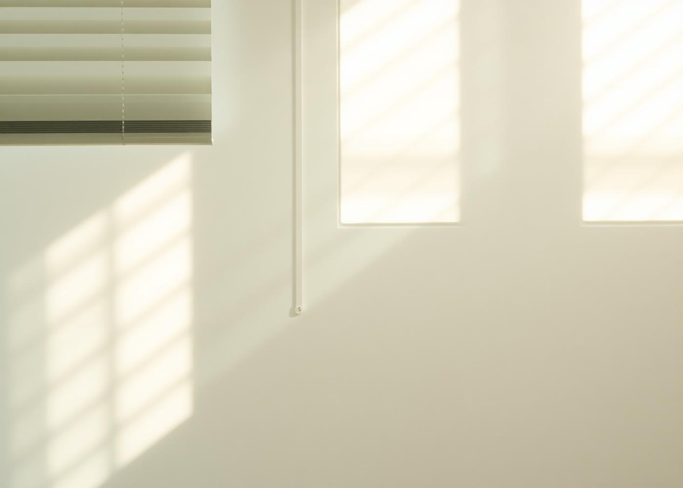 Soft light through window blinds on a white wall